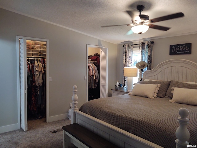 bedroom featuring ceiling fan, a spacious closet, a textured ceiling, and carpet floors