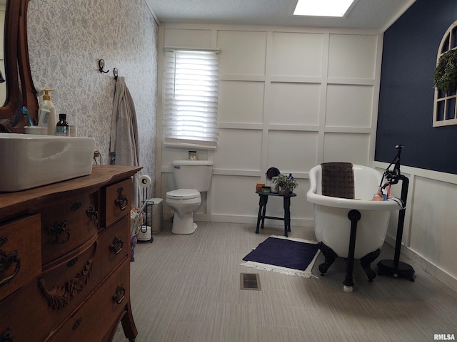 bathroom featuring a textured ceiling, toilet, and vanity