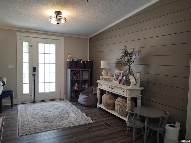 interior space featuring wood walls, wood-type flooring, plenty of natural light, and a textured ceiling