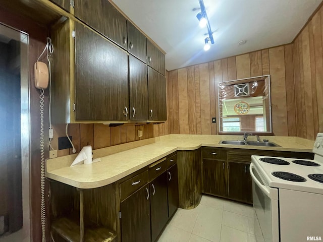 kitchen with wooden walls, white electric range, light tile patterned floors, sink, and kitchen peninsula