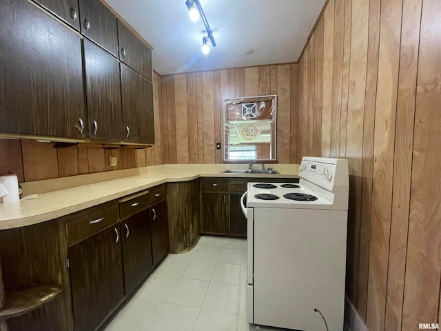 kitchen featuring wood walls, light tile patterned flooring, sink, rail lighting, and electric stove