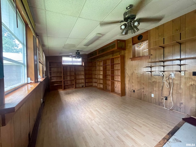 basement featuring wood walls, a paneled ceiling, built in features, ceiling fan, and hardwood / wood-style flooring