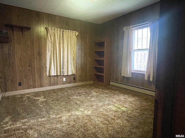 spare room featuring carpet, wooden walls, and baseboard heating