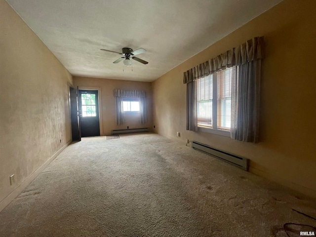 carpeted empty room featuring ceiling fan and a baseboard heating unit