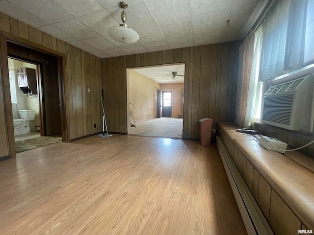 interior space featuring wood walls, a baseboard heating unit, light wood-type flooring, and ensuite bathroom