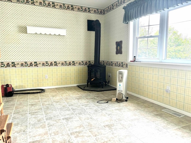 unfurnished living room with a wood stove and tile walls