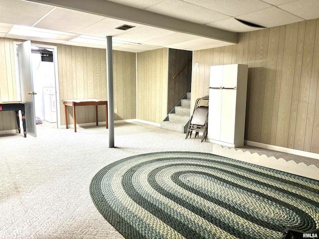 basement with white fridge, a paneled ceiling, wood walls, and carpet