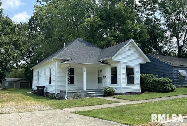 bungalow-style house with a shingled roof, covered porch, and a front lawn