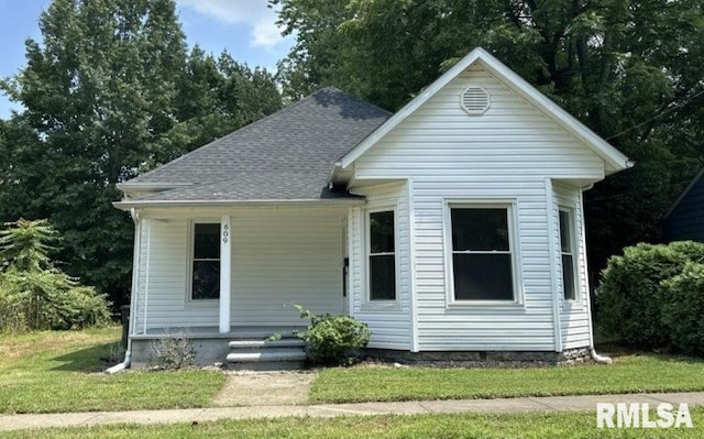 view of front of house featuring a shingled roof and a front yard