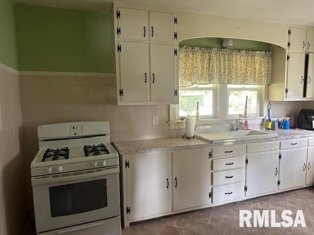 kitchen with white cabinets, white gas range, and sink