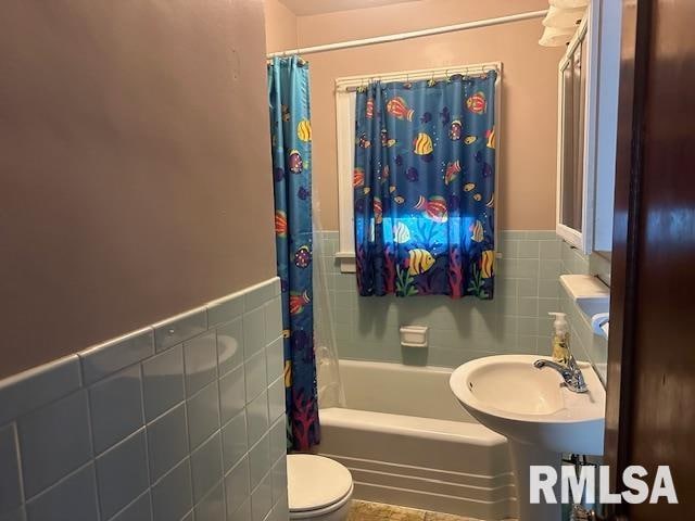 full bathroom featuring sink, shower / bath combo, toilet, and tile walls