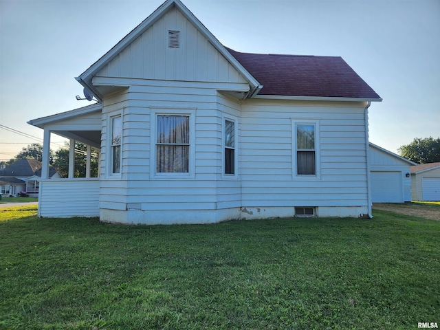 back of house with a garage, a yard, and roof with shingles