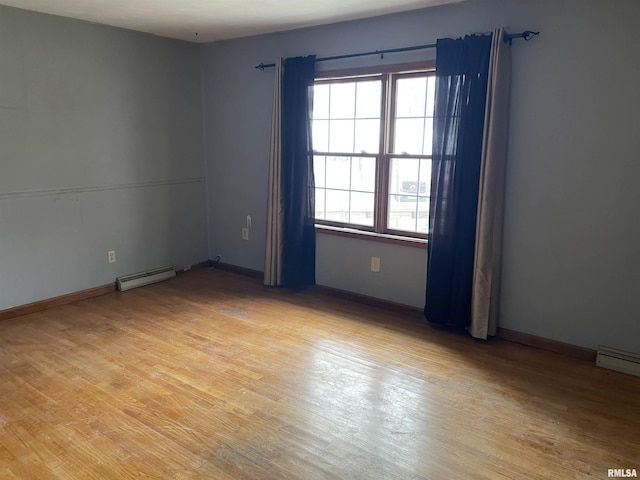 spare room featuring a baseboard heating unit and light hardwood / wood-style flooring