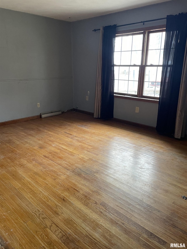 empty room featuring light hardwood / wood-style floors and a baseboard heating unit