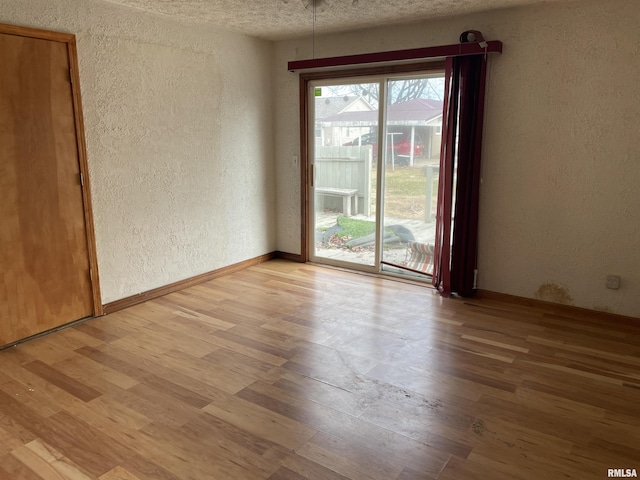 spare room with light hardwood / wood-style floors and a textured ceiling