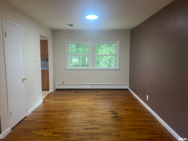 spare room with a baseboard radiator and wood-type flooring