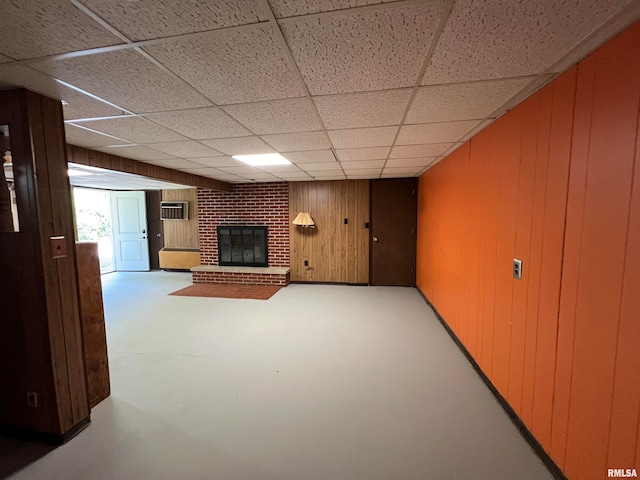 unfurnished living room featuring a fireplace, a paneled ceiling, concrete floors, and wood walls