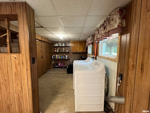 laundry room with washing machine and clothes dryer, cabinets, and wooden walls