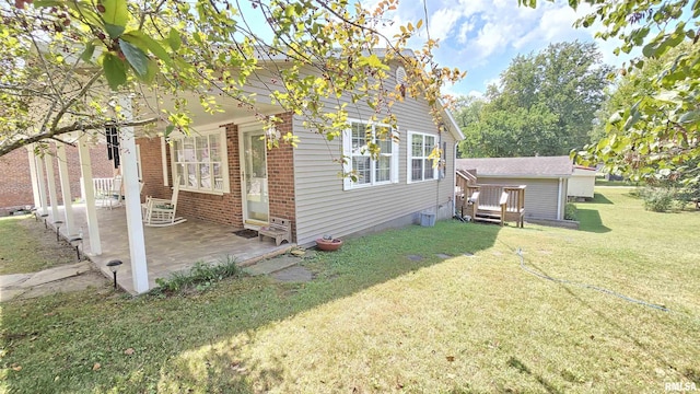 view of side of home with a yard, a patio area, and brick siding