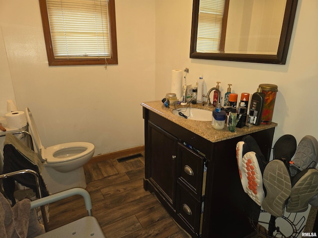 bathroom with hardwood / wood-style floors, toilet, a wealth of natural light, and vanity