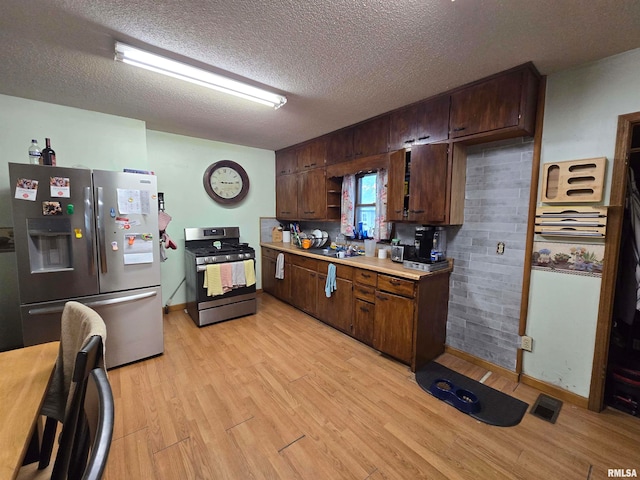 kitchen with light hardwood / wood-style floors, a textured ceiling, stainless steel appliances, decorative backsplash, and dark brown cabinetry