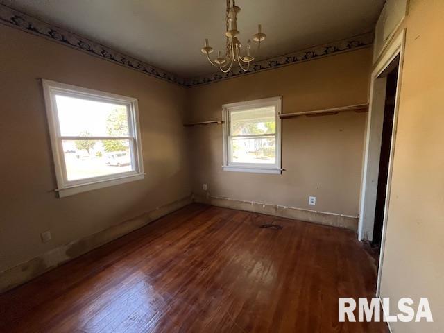 unfurnished bedroom with dark hardwood / wood-style floors, a chandelier, and multiple windows