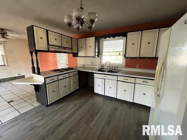 kitchen featuring white appliances, ceiling fan with notable chandelier, sink, hanging light fixtures, and dark hardwood / wood-style flooring