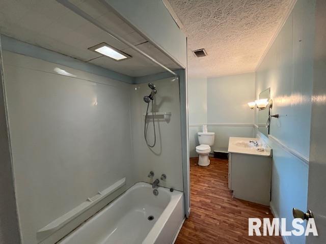 full bathroom featuring vanity,  shower combination, toilet, a textured ceiling, and wood-type flooring