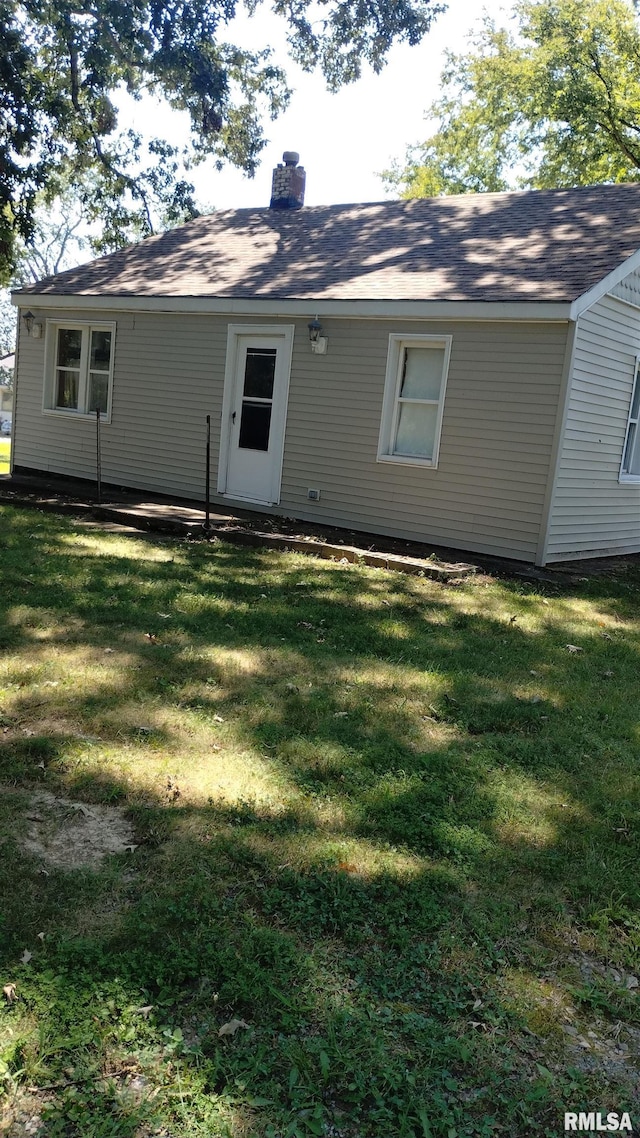 rear view of property featuring a yard and a chimney