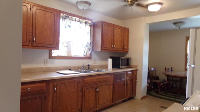 kitchen featuring light countertops, stainless steel microwave, a sink, and light floors