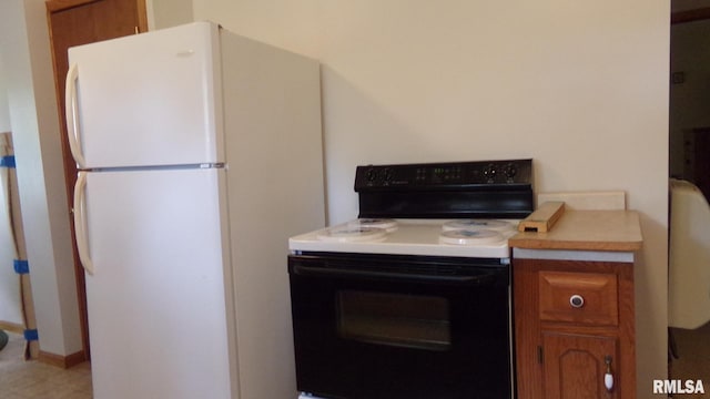 kitchen with brown cabinetry, light countertops, range with electric stovetop, and freestanding refrigerator