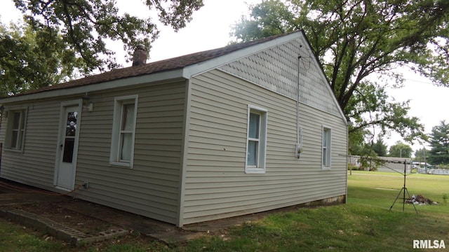 view of side of property with a yard and a chimney