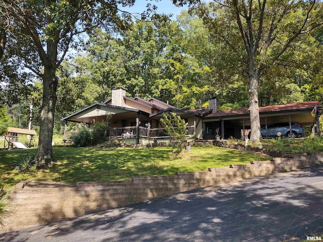 view of front of property featuring covered porch, a chimney, and a front lawn