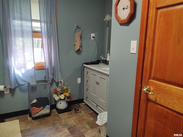 bathroom with stone finish flooring, baseboards, and vanity