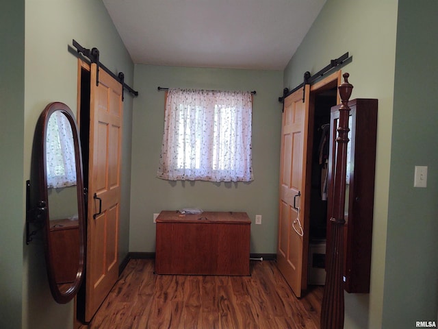 interior space with lofted ceiling, a barn door, and dark hardwood / wood-style flooring