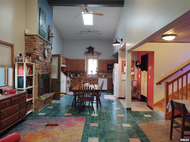 dining room with a fireplace, a towering ceiling, a ceiling fan, track lighting, and stairs