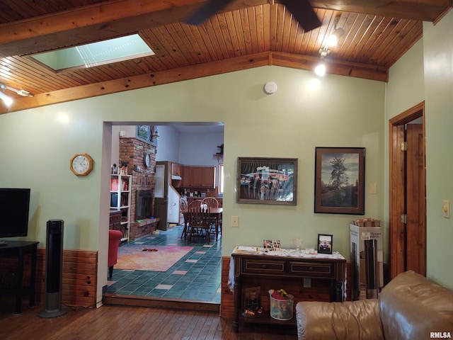 living area featuring vaulted ceiling with skylight, wood ceiling, wood-type flooring, and a brick fireplace