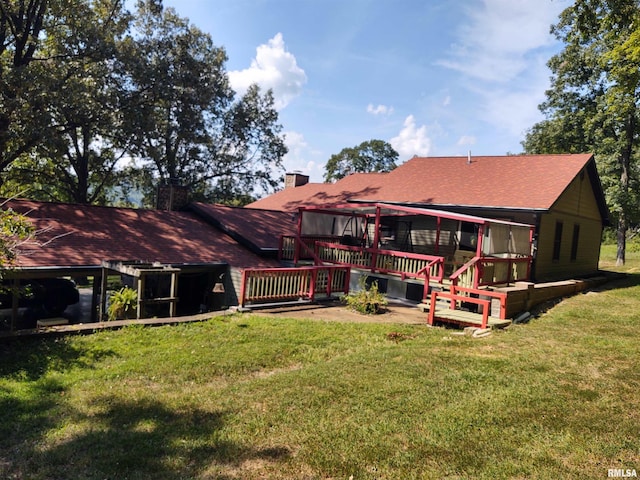 back of property with a lawn, a chimney, and a wooden deck