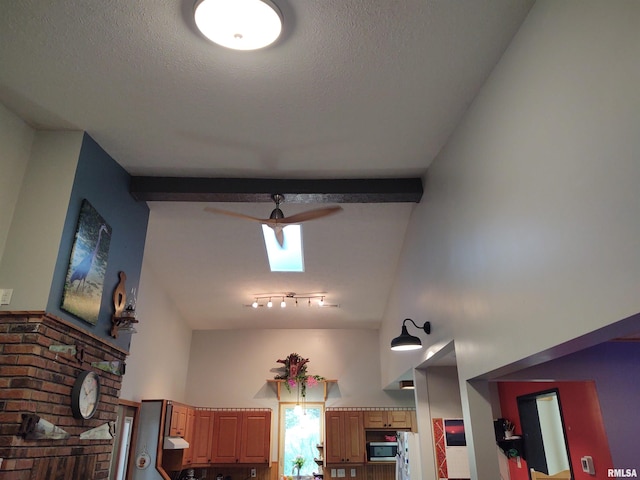 details featuring a skylight, ceiling fan, beamed ceiling, and a textured ceiling