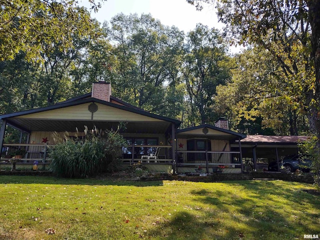 back of property with covered porch, a lawn, and a chimney