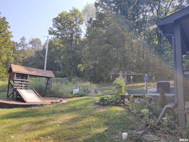 view of yard featuring a forest view and a playground