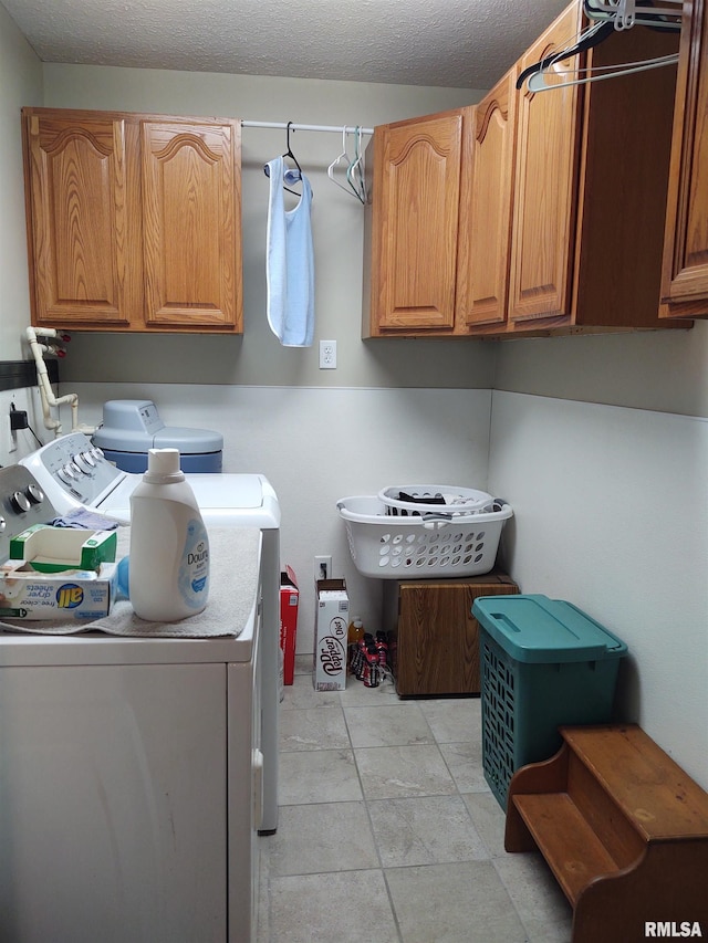 clothes washing area featuring light tile patterned floors, a textured ceiling, cabinets, and washing machine and dryer