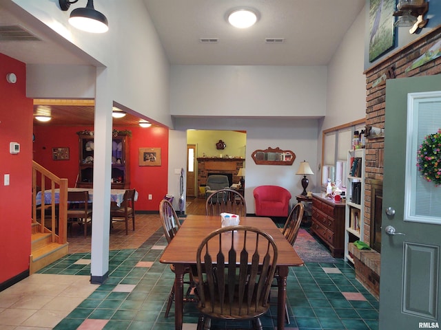 tiled dining space with stairway, a fireplace, visible vents, and baseboards