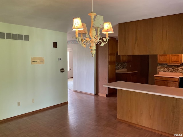 kitchen featuring pendant lighting, tasteful backsplash, parquet flooring, and a notable chandelier