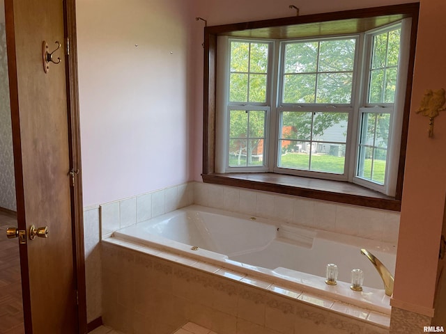 bathroom with a healthy amount of sunlight and a relaxing tiled tub