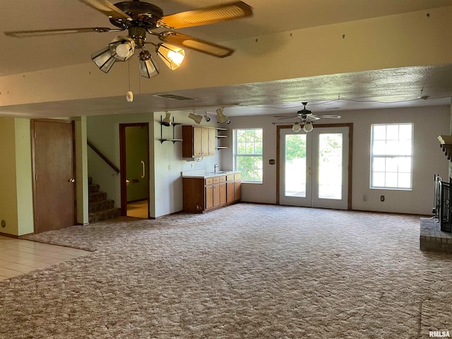 unfurnished living room featuring carpet flooring, ceiling fan, and sink