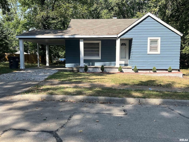 view of front of home featuring driveway, a shingled roof, an attached carport, covered porch, and a front lawn