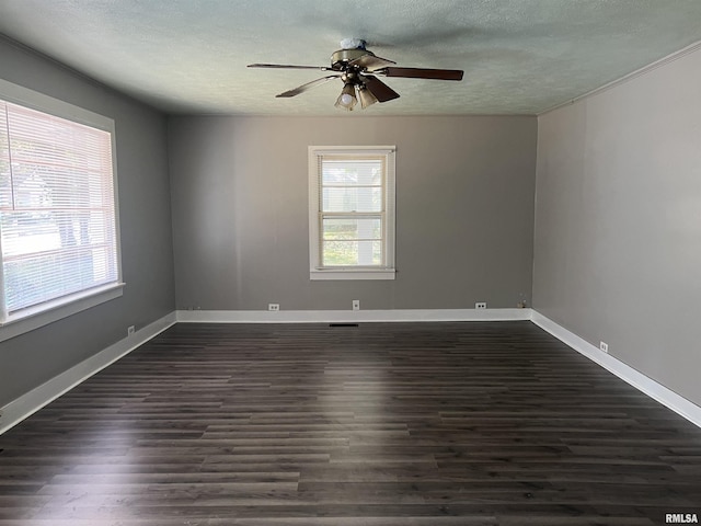 spare room featuring dark wood-style floors, plenty of natural light, a textured ceiling, and baseboards