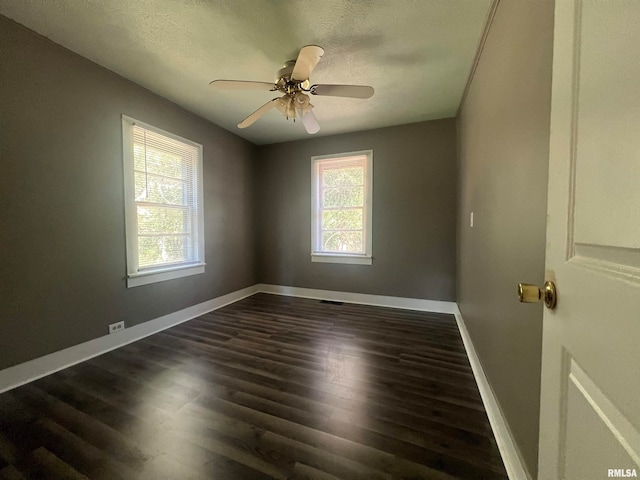 empty room with ceiling fan, plenty of natural light, dark hardwood / wood-style flooring, and a textured ceiling