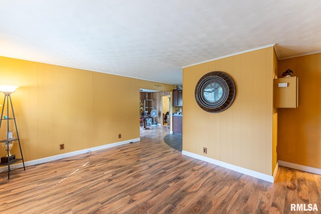 unfurnished room featuring wood walls, crown molding, and hardwood / wood-style flooring